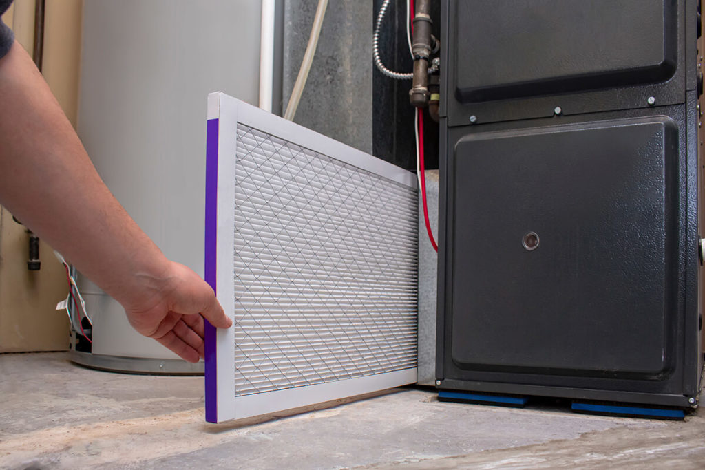 A person changing an clean air filter on a high efficiency furnace A person changing an clean air filter on a high efficiency furnace