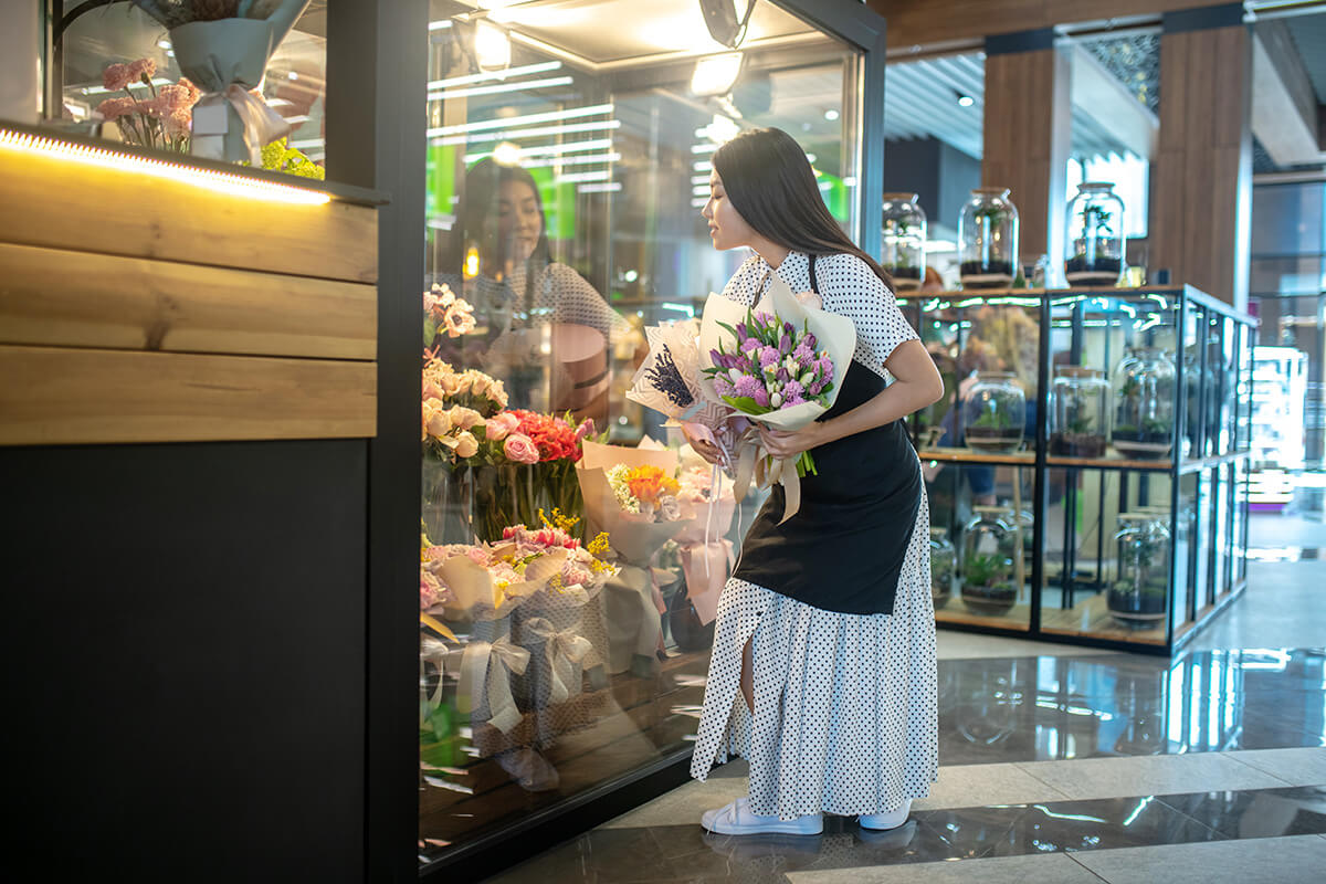 runette female in apron standing with bouquets